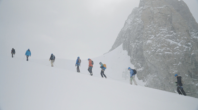 Groupe de personnes encordées dans des montagnes enneigées